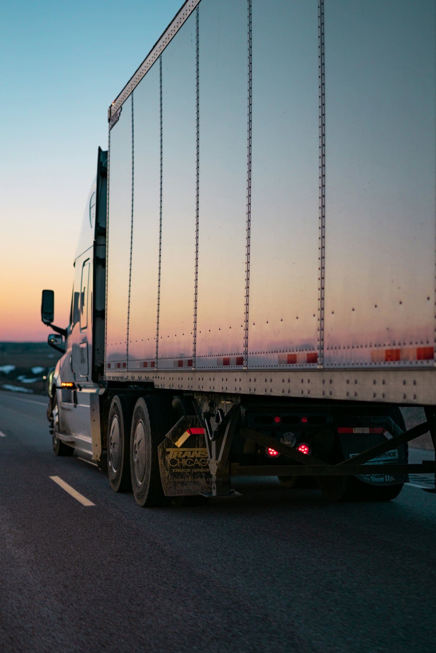 White freight truck travelling along an open road during daytime