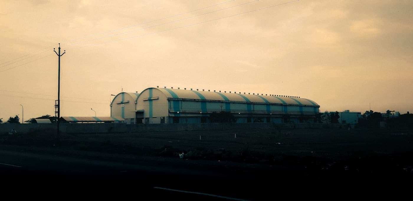 Large dimly lit industrial building interior with sweeping roof
