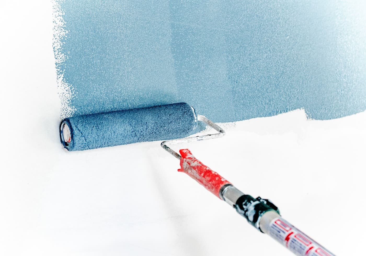 Painter using a roller on an interior wall in warm afternoon light