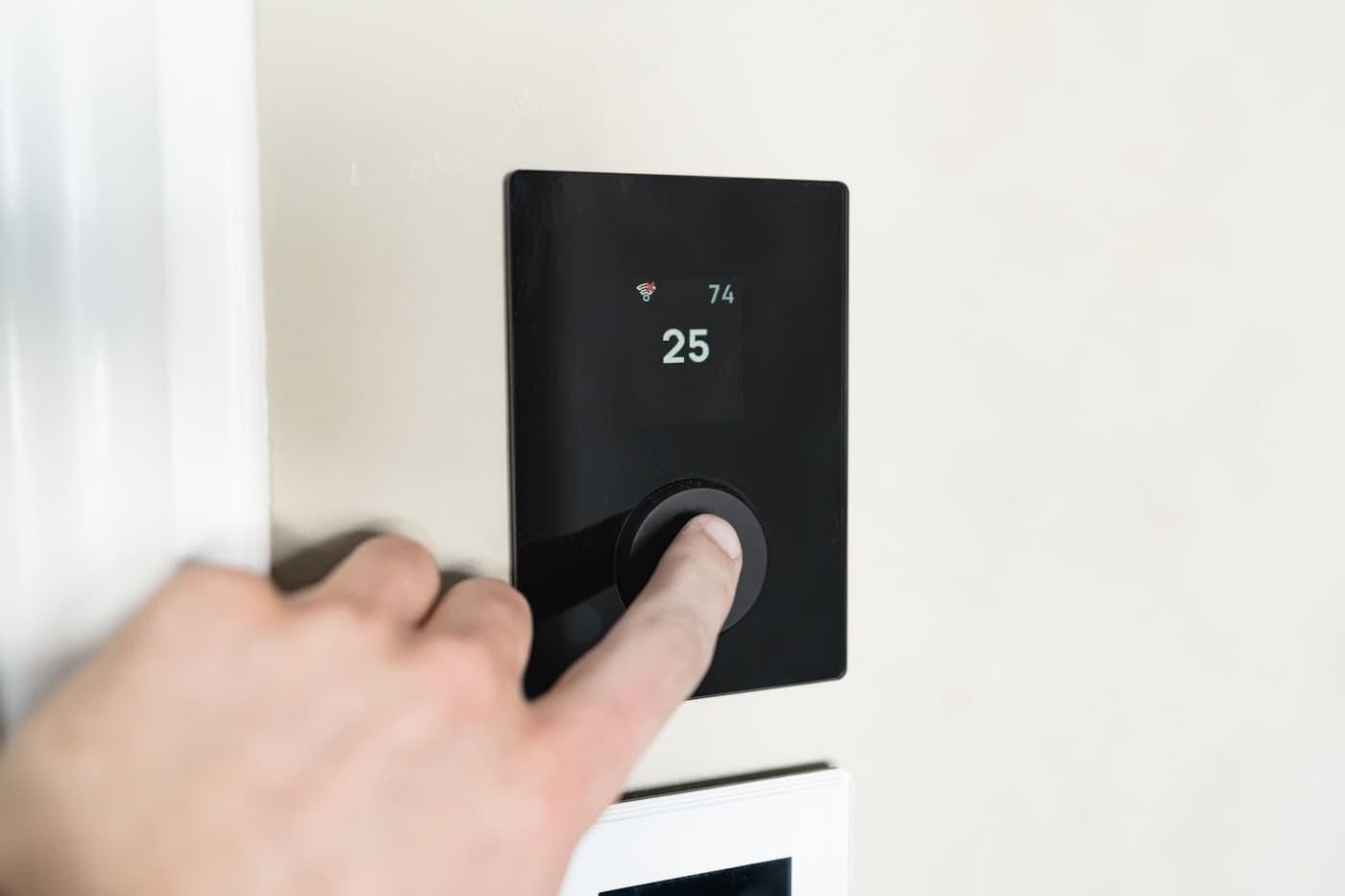 Finger pressing a button on a digital thermostat display