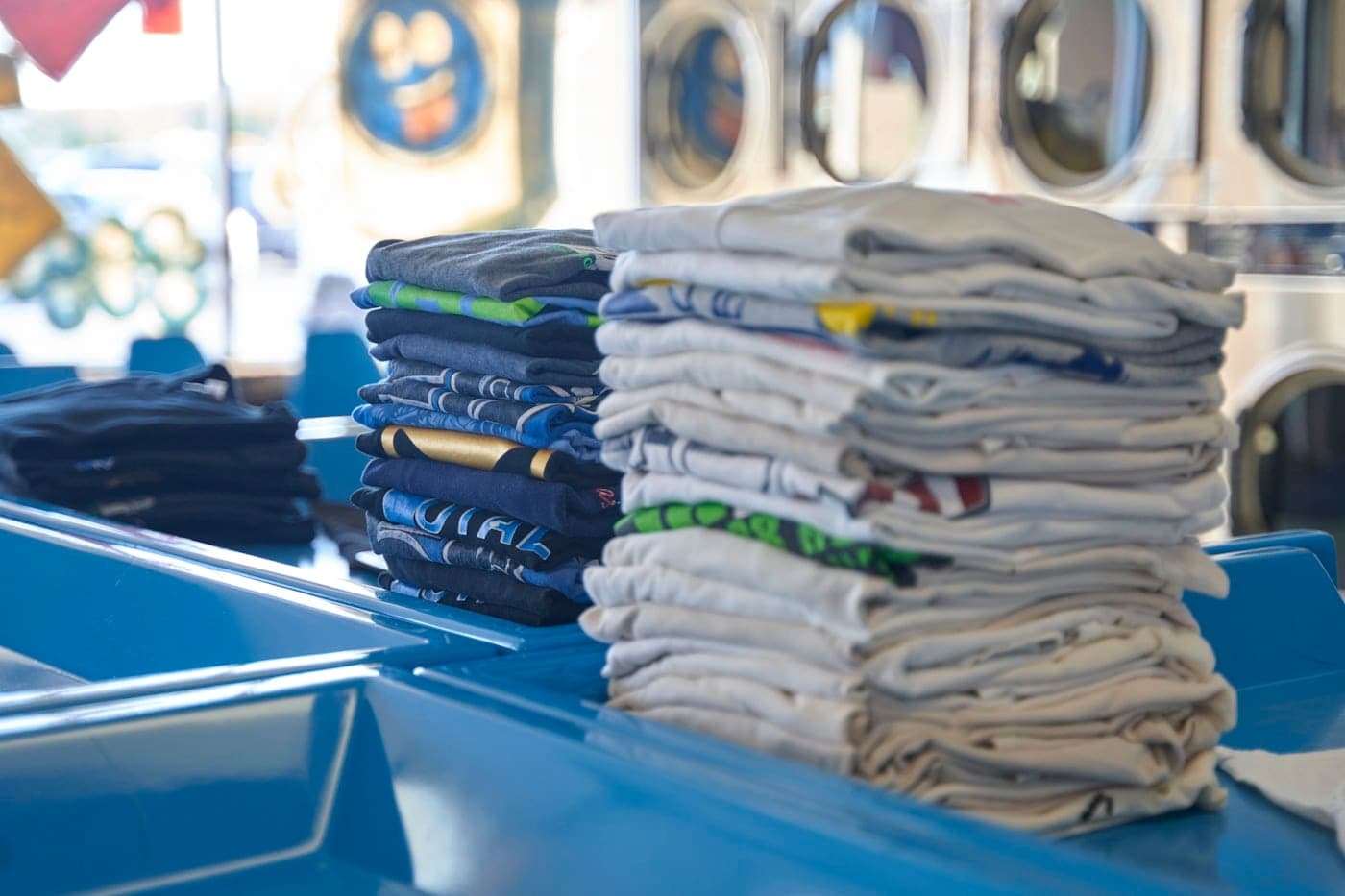 Tall stack of freshly folded shirts resting on a blue surface
