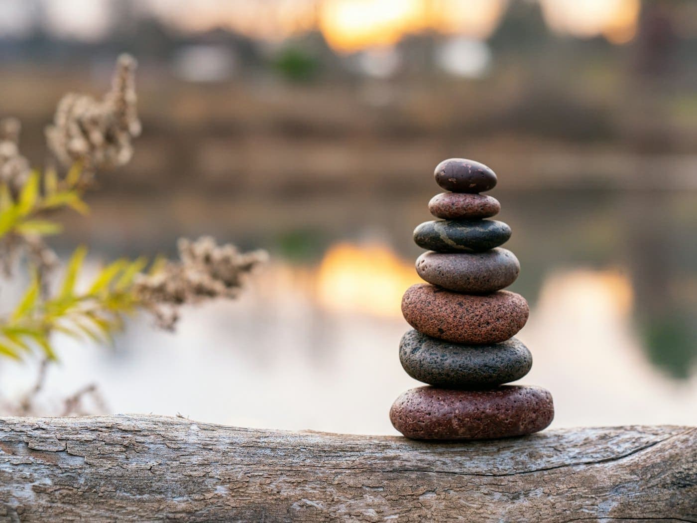 Quiet stack of smooth brown stones balanced on a wooden log
