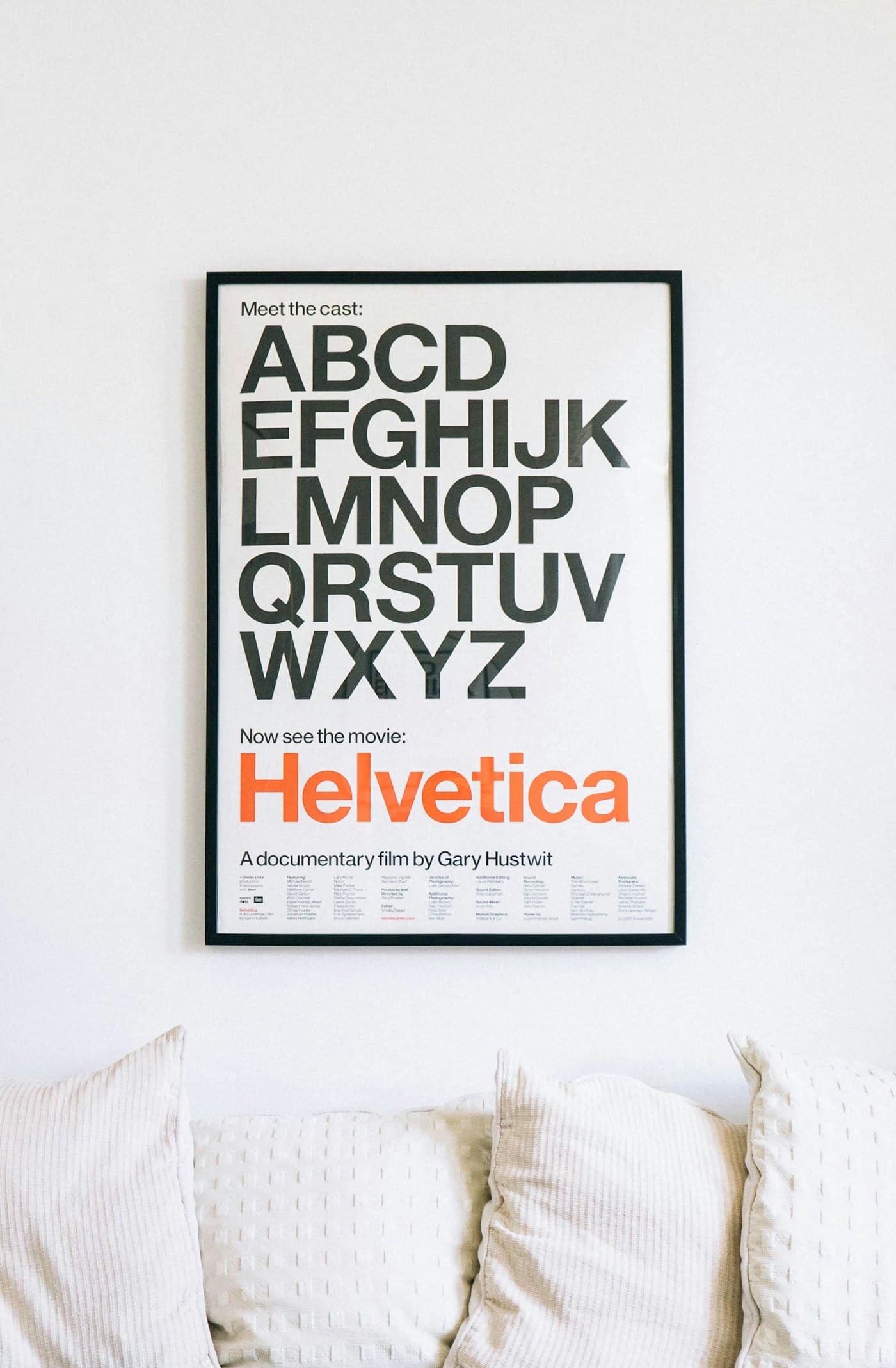 Wall-mounted Helvetica alphabet poster hung above a sofa