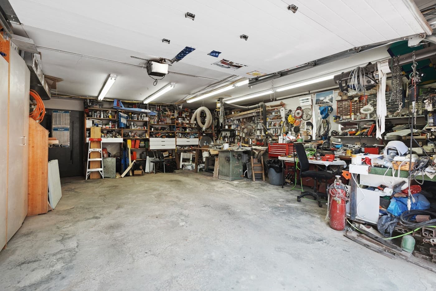 Residential garage filled with stacked clutter and stored tools